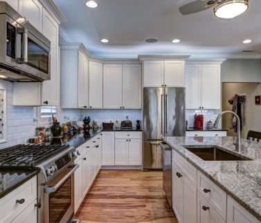 High-end luxury kitchen with granite countertops and white cabinets.